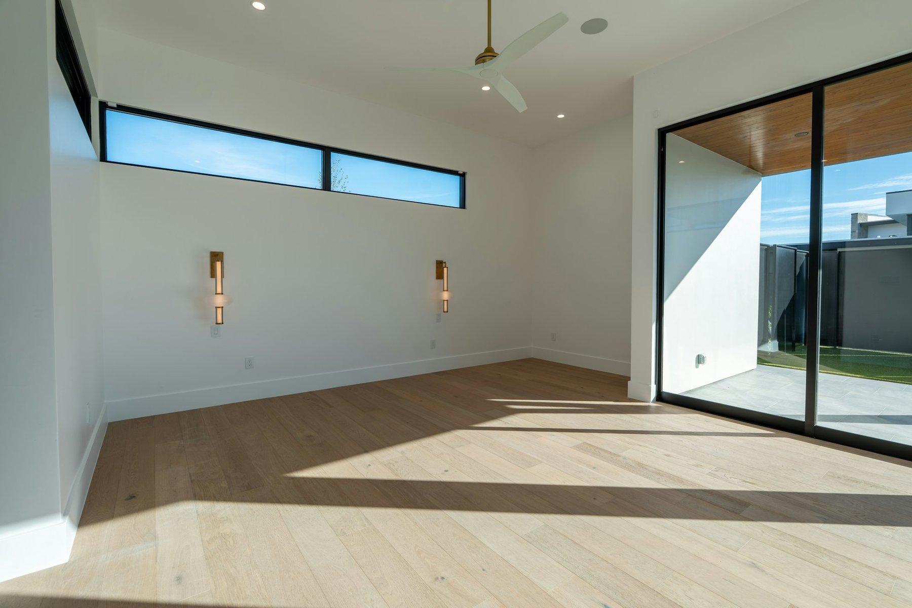 An empty, sunlit living room with light oak floors and large windows — the starting canvas.